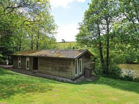 A wooden cabin surrounded by trees and grass at 11 Water's Edge near Pelynt