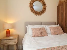 A bedroom with a bed, nightstand, and mirror at Sea Vista in Westward Ho!