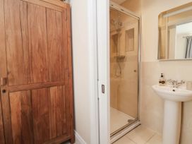 A bathroom with a shower, sink, mirror, and wooden cabinet at Sea Vista in Westward Ho!