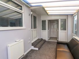 A conservatory with a sofa and door at Ger y Mynydd, 2 Cae Ty Coch, Brynteg