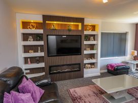 A living room with a tv and shelves at Ger y Mynydd, 2 Cae Ty Coch Brynteg