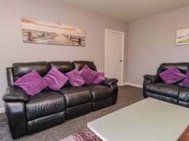 A living room with black sofas and a coffee table at Ger y Mynydd, 2 Cae Ty Coch in Brynteg