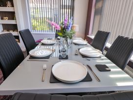 A dining room with a set table and floral arrangement at Ger y Mynydd, 2 Cae  Ty Coch Brynteg