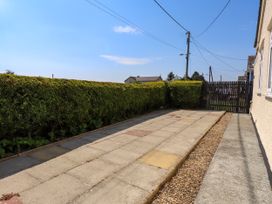 An outdoor area with paving stones and a hedge at Ger y Mynydd, 2 Cae Ty Coch in Brynteg