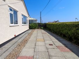 A pathway alongside a house with bushes and windows at Ger y Mynydd, 2 Cae Ty Coch in Brynteg