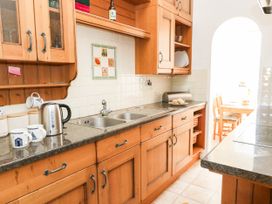 A kitchen with wooden cabinets and dining table at Flat 3, 4 Park Road in Swanage