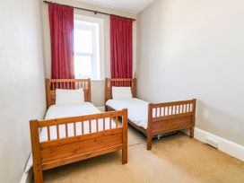 A bedroom with two single beds and red curtains at Flat 3, 4 Park Road in Swanage