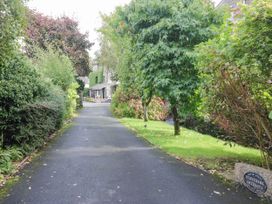 A pathway lined with trees and shrubs leading to a house at Rooftops in Lindale