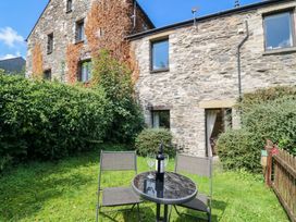 A garden with a stone building and table set at Rooftops in Lindale