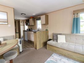 A living room with a kitchen area and seating at Kensington 49