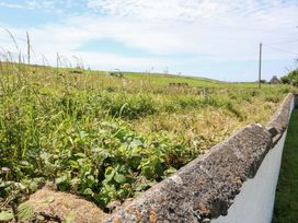 A view of grass and stone wall along a field with a sky at Tach Ferme in 