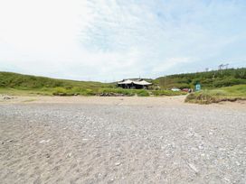 A beach with grass and a building in the background at Tach Ferme