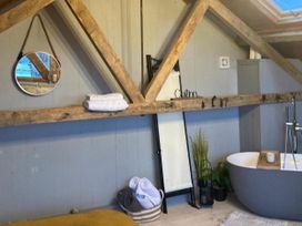 A bathroom with a bathtub and towels at 1-Bed Barn Conversion, Sleeps 2 with Parking, Niwbwrch (newborough)