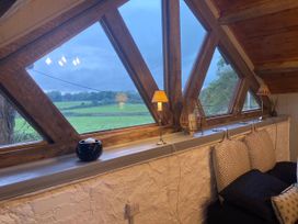 A living room with large windows overlooking a green landscape at 1-Bed Barn Conversion, Sleeps 2 with Parking, Niwbwrch (newborough)