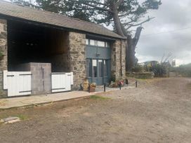 A barn exterior with stone walls and wooden doors at 1-Bed Barn Conversion, Sleeps 2 with Parking, Niwbwrch (newborough)