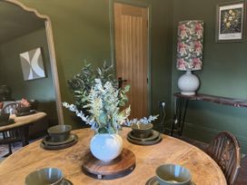A dining room with a table set and a vase of foliage at Llysawelon 2-Bed Cottage, Sleeps 5, Pets Ok in Llysawelon near Llansteffan