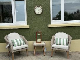 An outdoor seating area with two chairs, a table, and a clock at Llysawelon 2-Bed Cottage, Sleeps 5, Pets Ok near Llysawelon