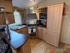 A kitchen with appliances and wooden cabinetry at 2-Bed Caravan, Sleeps 6 w/ Parking, No Pass Needed