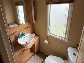 A bathroom with sink, toilet, and window at 2-Bed Caravan, Sleeps 6 w/ Parking, No Pass Needed