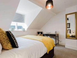 A bedroom with a bed, mirror, and table at Licatas Apartment Cirencester Cotswolds Sleeps 6