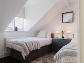 A bedroom with two beds and a nightstand at Licatas Apartment Cirencester Cotswolds Sleeps 6
