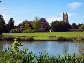 A view of a park with a river and a tower at Licatas Apartment Cirencester Cotswolds Sleeps 6