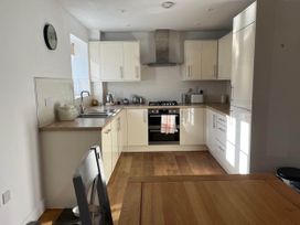 A kitchen with cabinets, sink, stove and dining table in Apartment Sleeps 4 with Parking Chagford