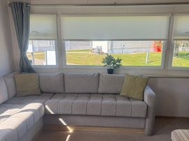 A living room with a sofa and a plant at Caravan - Sleeps 6 - Parking in Lossiemouth