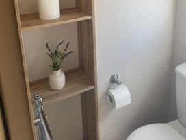 A bathroom with a toilet and shelves containing a plant at Caravan - Sleeps 6 - Parking in Lossiemouth