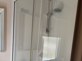 A shower with a showerhead and a mirror at Caravan - Sleeps 6 - Parking Lossiemouth