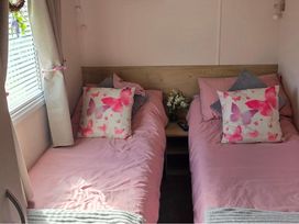 A bedroom with two single beds and a table at D&T Caravan Hire Southview Holiday Park Skegness