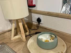 A table with a lamp and a candle at Coworth Deluxe Cabin with Garden