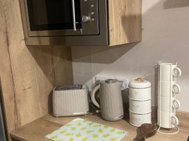 A kitchen with a microwave, toaster, kettle, and storage canisters at Coworth Deluxe Cabin with Garden