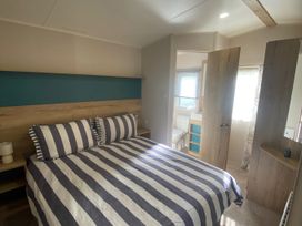A bedroom with a bed and adjoining bathroom at Coworth Deluxe Cabin with Garden