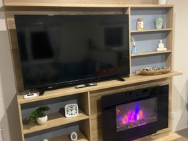 A living room with a television and electric fireplace at Coworth Deluxe Cabin with Garden
