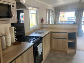 A kitchen with stove and sink at Coworth Deluxe Cabin with Garden
