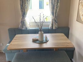 A dining area with a table and bench seating at Coworth Deluxe Cabin with Garden