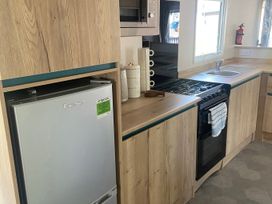 A kitchen with a refrigerator, microwave, and gas stove at Coworth Deluxe Cabin with Garden