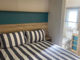 A bedroom with a bed and a toilet in the corner at Coworth Deluxe Cabin with Garden