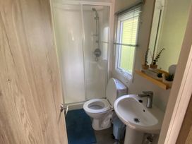 A bathroom with a shower, toilet, and sink at Coworth Deluxe Cabin with Garden
