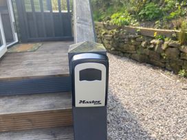 A lock box on a stair railing next to a stone wall at Coworth Deluxe Cabin with Garden