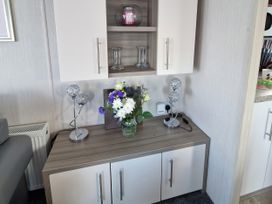 A cabinet with a vase of flowers and lamps in a living room at Caravan Sleeps 6 with Sea Views and Parking in Ayr