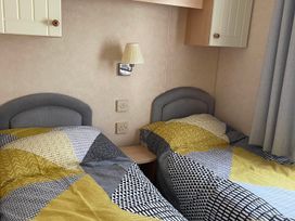 A bedroom with two single beds and a bedside lamp at Beautiful 2 Bed Static caravan