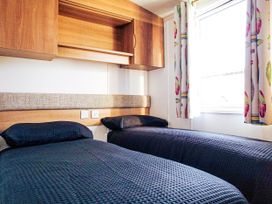 A bedroom with two single beds and wooden cupboards at Captivating 6-Person Caravan in Rhyl