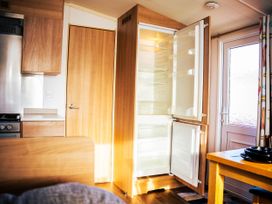 A kitchen with an open refrigerator and a door at Captivating 6-Person Caravan in Rhyl