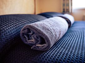 A rolled towel on bed linens at Captivating 6-Person Caravan in Rhyl