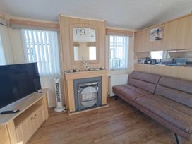 A living room with a sofa and television at Sea and Mountain view Sunbeach Holiday Snowdonia in Llwyngwril
