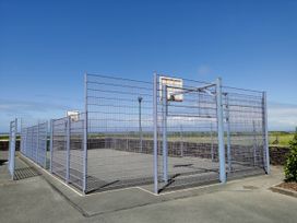 A basketball court enclosed by a fence at Sea and Mountain view Sunbeach Holiday Snowdonia Llwyngwril