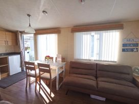 A living room with a dining area and refrigerator at Sea and Mountain view Sunbeach Holiday Snowdonia