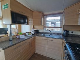 A kitchen with a microwave, kettle, and sink at Sea and Mountain view Sunbeach Holiday Snowdonia in Llwyngwril